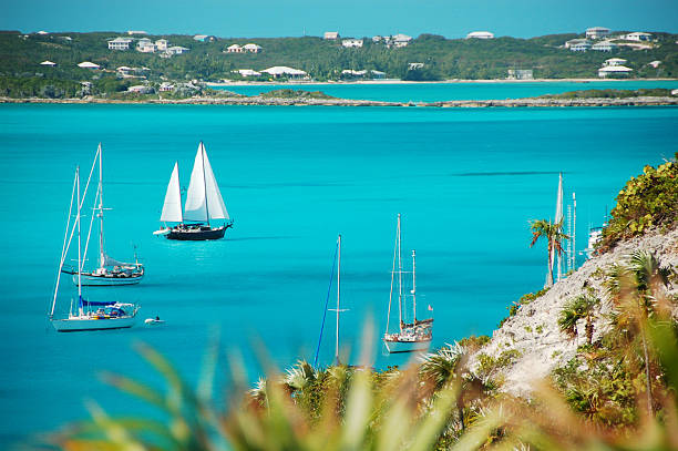 Sailboat in the Bahamas "A sailboat travels past Stocking Island, Exuma, in the Bahamas." exuma stock pictures, royalty-free photos & images