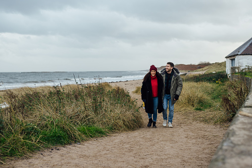 Rear view image of a mature female couple walking along the beach on a cold day