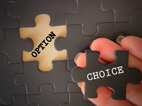 OPTION and CHOICE written on jigsaw puzzle pieces. With blurred styled background.