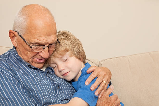 Grandfather and Grandson Resting on a Couch A grandfather is resting on a couch with his seven year old grandson. sleeping grandpa stock pictures, royalty-free photos & images