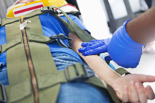 Ambulance medic putting needle into injured patient on stretcher Ambulance medic putting needle into injured patient on stretcher. restraining device stock pictures, royalty-free photos & images