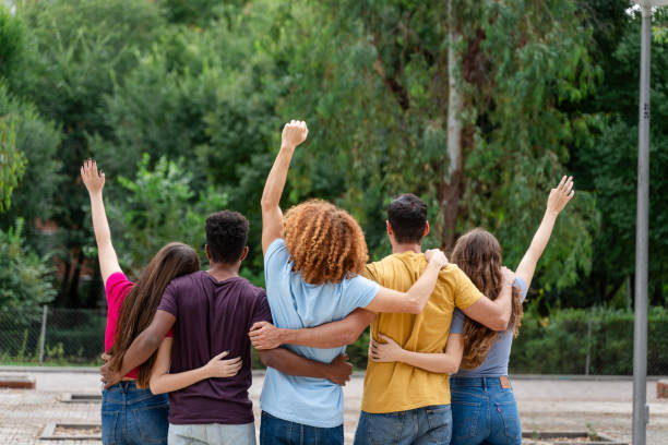 istock back view of multicultural friends with raised hands looking at each other in park 1754383655