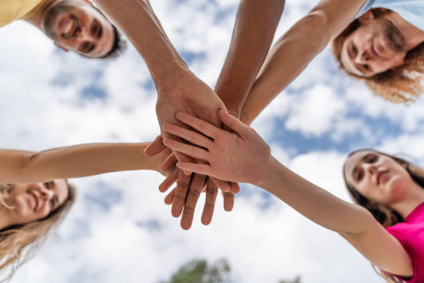 istock Low angle view of a group of young people stacking their hands together 1754384332