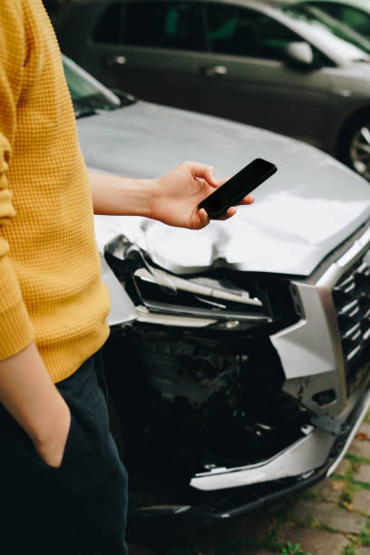 istock Man using smartphone standing next to the crashed car after the accident 1754386574
