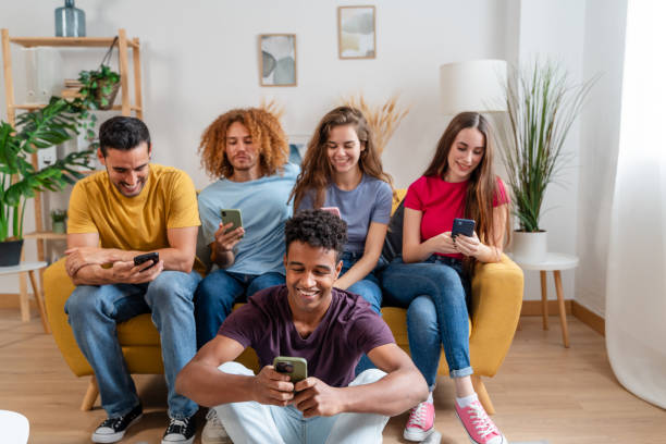 multiethnic group of young people using mobile phones while sitting on sofa at home
