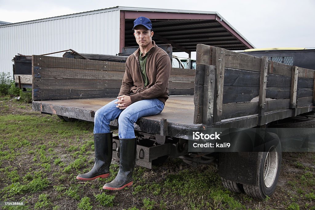 Farmer sitting on back of truck Farmer (40s) sitting on back of truck. Farmer Stock Photo