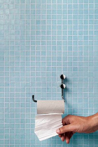 Hand pulling last square of toilet paper from the roll