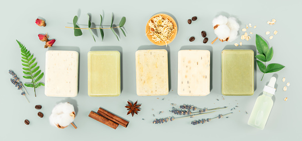 Sustainable lifestyle concept. Bars of natural handmade soap and ingredients on blue background, top view banner