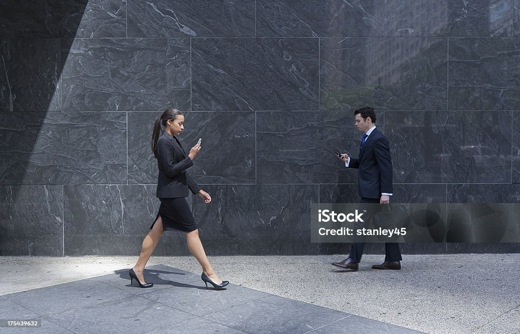 Casal com telefones celulares negócios andando em uma cidade de Calçada - Foto de stock de 20 Anos royalty-free