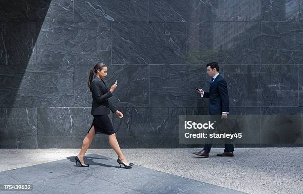 Foto de Casal Com Telefones Celulares Negócios Andando Em Uma Cidade De Calçada e mais fotos de stock de 20 Anos