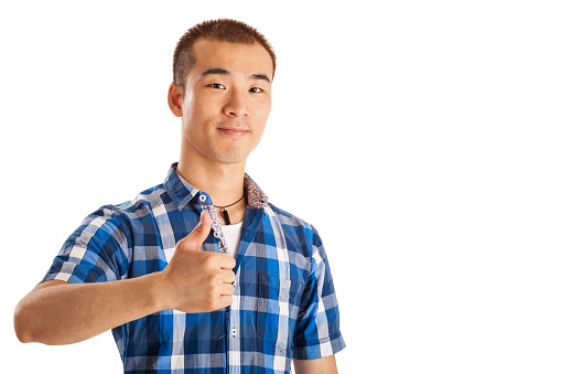 Optimistic,confident young chinese man with hand raised, showing thumb up.Studio shot on white background.