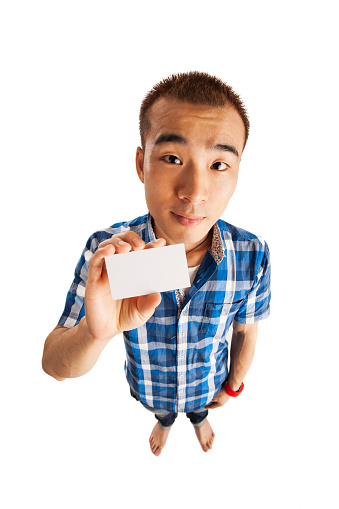 Wide angle image of Asian man, holding a blank business card.
