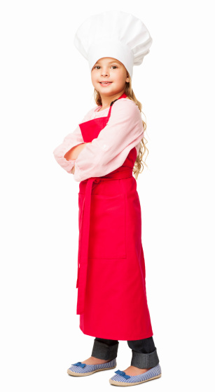 Full length portrait of a cute little girl dressed up as a chef standing with arms crossed. Vertical shot. Isolated on white.
