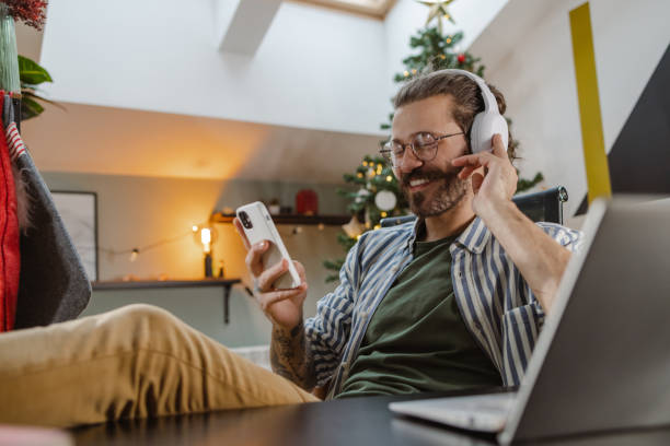 istock Relaxed man in cozy Christmas atmosphere using a smart phone 1754405687