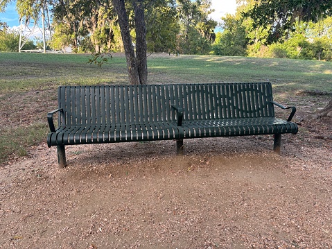 Very large green sitting bench on walking path in public park