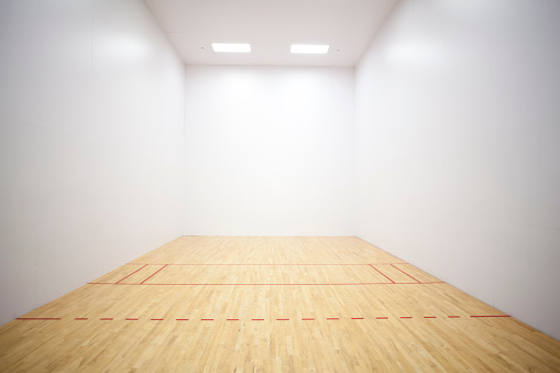 Empty racquetball court with wood floor and lines.
