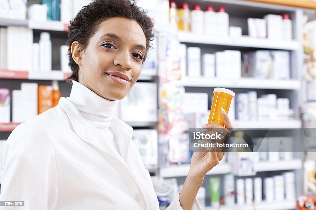 Jovem feminino farmacêutico segurando uma garrafa de comprimido - Foto de stock de Farmacêutico royalty-free