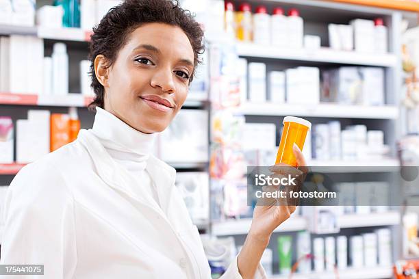 Foto de Jovem Feminino Farmacêutico Segurando Uma Garrafa De Comprimido e mais fotos de stock de Farmacêutico