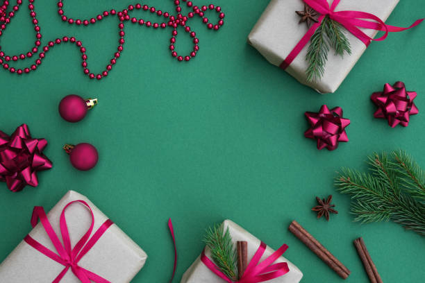 istock Christmas frame with gift boxes, paper decorations, bells and fir branches on a turquoise background. 1754411043