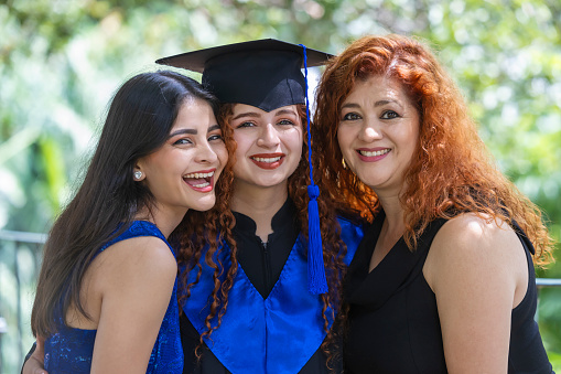Family portrait of mother and two daughters at the graduation of the youngest daughter.