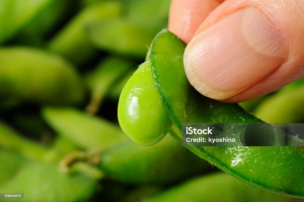 Segurando um verde fresco cozido de soja contra verde soja - Foto de stock de Amontoamento royalty-free