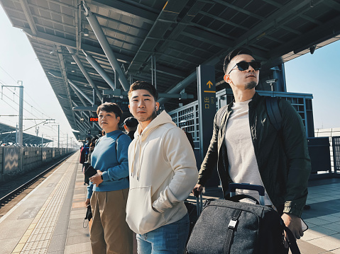 Asian chinese friends traveling together waiting high speed train to kaohsiung in train station platform in the morning