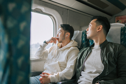 Asian Chinese tourist gay couple traveling high speed train to Kaohsiung