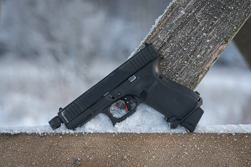 Pistol in a wooden surface with snow in winter, side view, close up photo