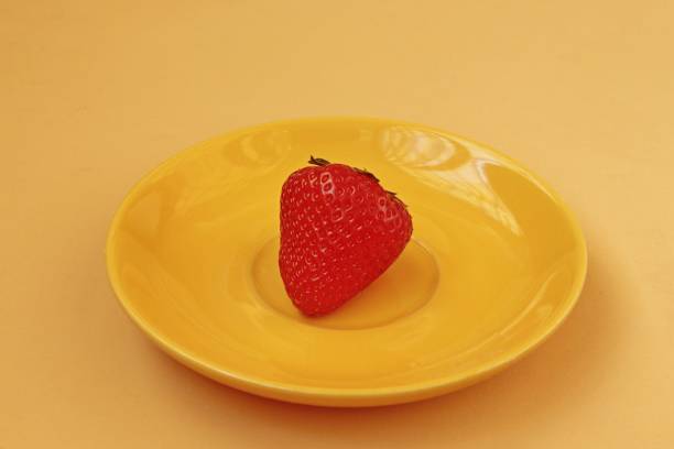 Strawberries are depicted on a yellow saucer.