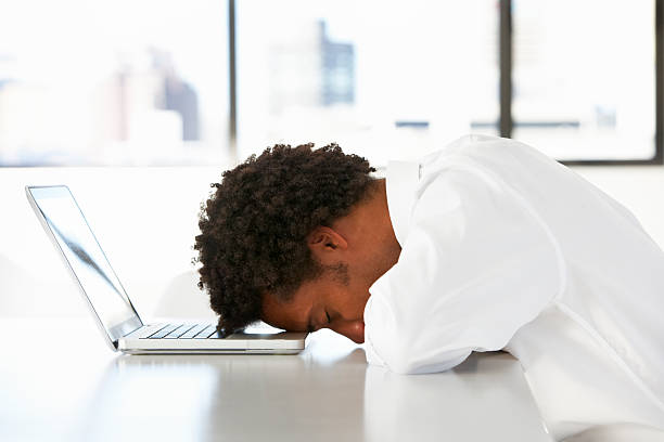 frustré homme d'affaires, assis au bureau pour travailler dans le bureau avec ordinateur portable - tête penchée photos et images de collection