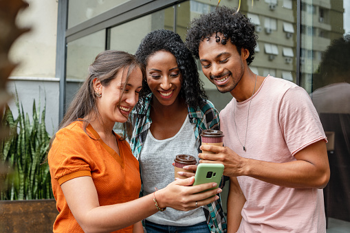 brazilian woman showing mobile screen to friends in coffee shop