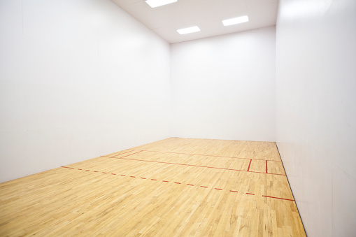 Empty racquetball court with wood floor and lines.
