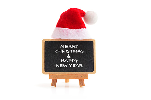 Black small chalkboard with text  Merry Christmas and Happy New Year and Santa hat on white background