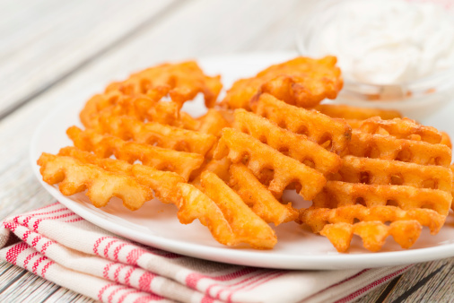 Close-up of potato waffle fries and a sour cream and chive dip - studio shot