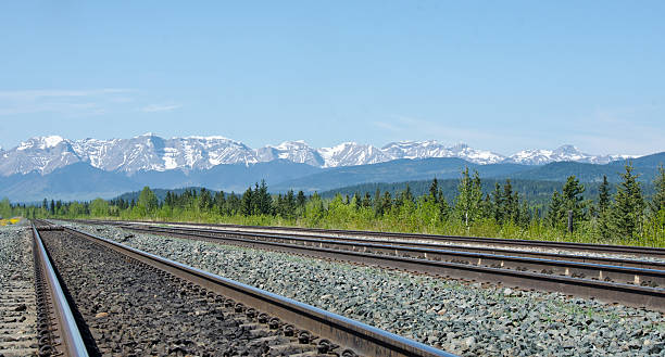 Train Tracks to the Rockies Looking down a pair of railroad tracks leading to the Rocky Mountains. In Hinton, Alberta hinton alberta stock pictures, royalty-free photos & images