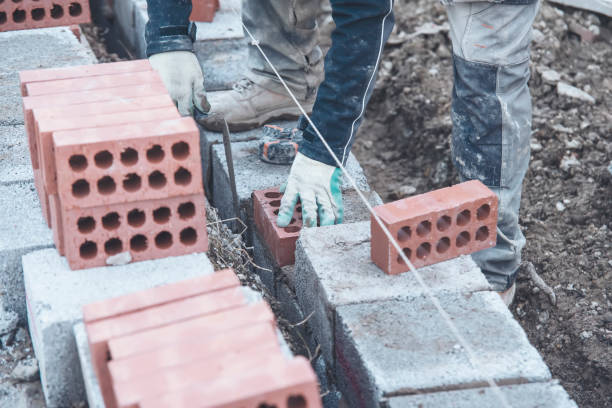 murarz układający cegłę na mieszance cementowej na budowie z bliska. zmniejsz kryzys mieszkaniowy, budując bardziej przystępne cenowo domy - cenowo zdjęcia i obrazy z banku zdjęć