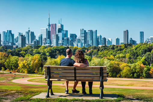 Couple enjoys the skyline of Toronto, Ontario, Canada while sitting on a bench.