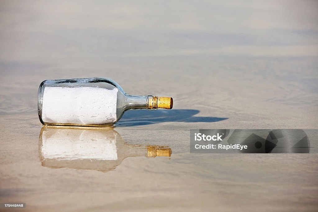 Bottle stranded on beach contains blank message Modern castaway's message in a bottle is blank - you can add any message you like! Announcement Message Stock Photo