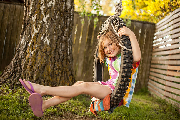 colore giovane ragazza in altalena con pneumatico tie dye camicia parete - freedom tire swing tire swing foto e immagini stock