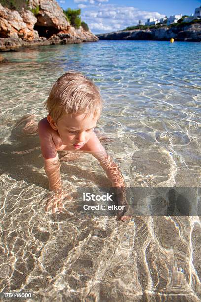 Piccolo Ragazzo Alla Ricerca Di Conchiglie In Acqua Alla Spiaggia Di Sabbia - Fotografie stock e altre immagini di 2-3 anni