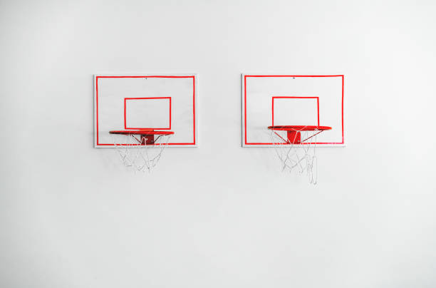 istock Two basketball backboards with red metal hoops on white concrete wall 1754460203