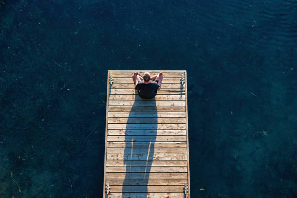 Man meditating on a pier, as seen from above.