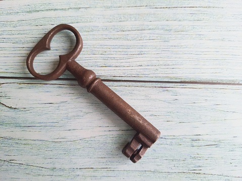 Old vintage rusty key isolated on an antique wooden table with space for text.