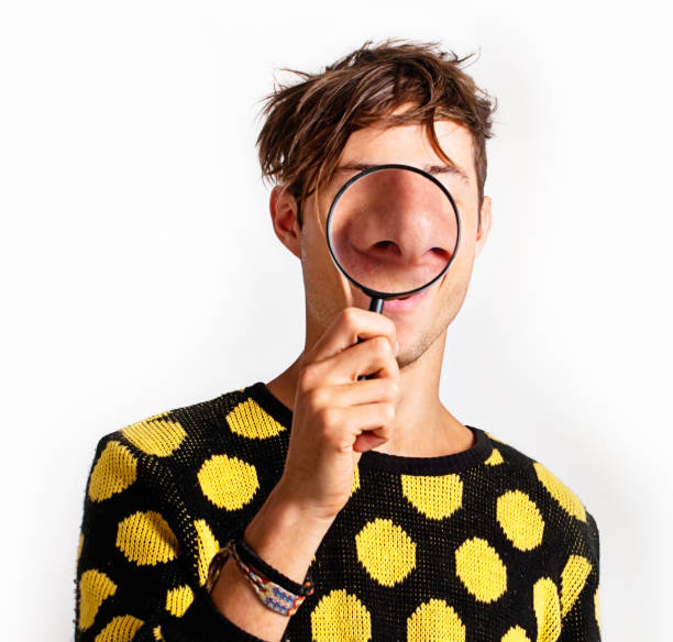 istock Magnifying glass enlarges young man's nose hugely and humorously 175446452