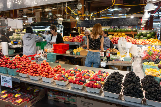 Fruit stall in Granville Island Public Market, Vancouver, Canada A fresh fruit stall in Granville Island Public Market, Vancouver, Canada, where vendors sell fruits such as blackberries, strawberries, physalis, blueberries, apples, watermelons and kiwi fruit. Stallholders are serving customers. granville island stock pictures, royalty-free photos & images