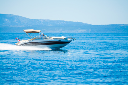 Aerial top view of a motor powerboat forming a circle of waves and bubbles with its engines over the blue sea