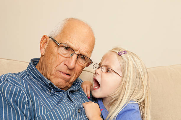 Child Girl Yelling into Grandfather's Ear "A four year old girl is yelling into her, hard of hearing, confused grandfather's ear." deafness photos stock pictures, royalty-free photos & images