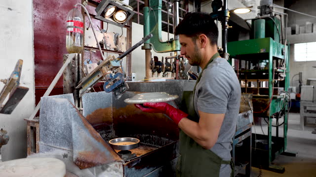 Latin American employee working at a pottery factory making a beautiful plate