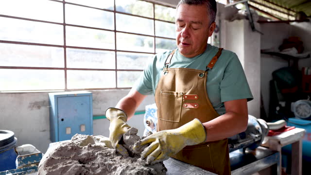 Mature craftsman kneading a bulk of clay getting the air out before shopping it