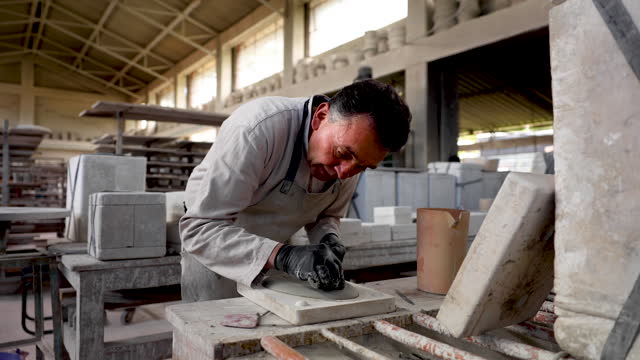 Male artisan giving final touches to a fresh plate still on mold at a pottery factory